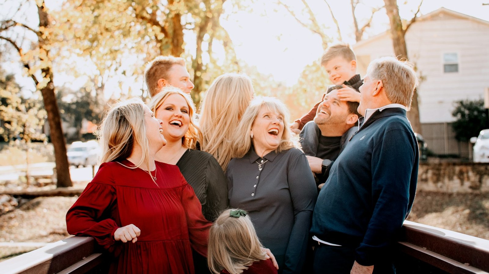 A multigenerational family laughing together outdoors on a fall day