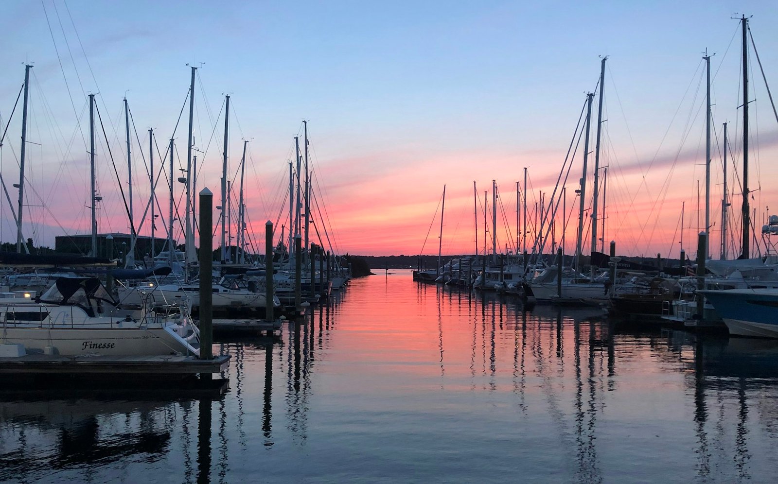 Sailboats moored at a marina under a pink and blue sunset sky