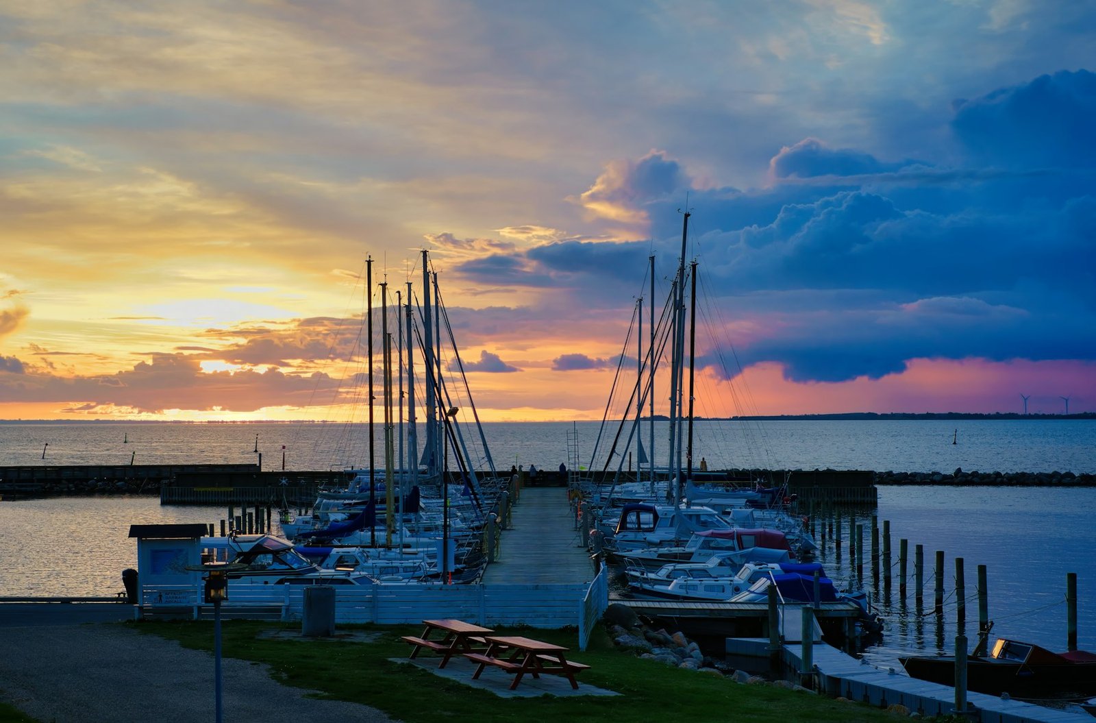 A marina full of sailboats at golden hour with dramatic clouds