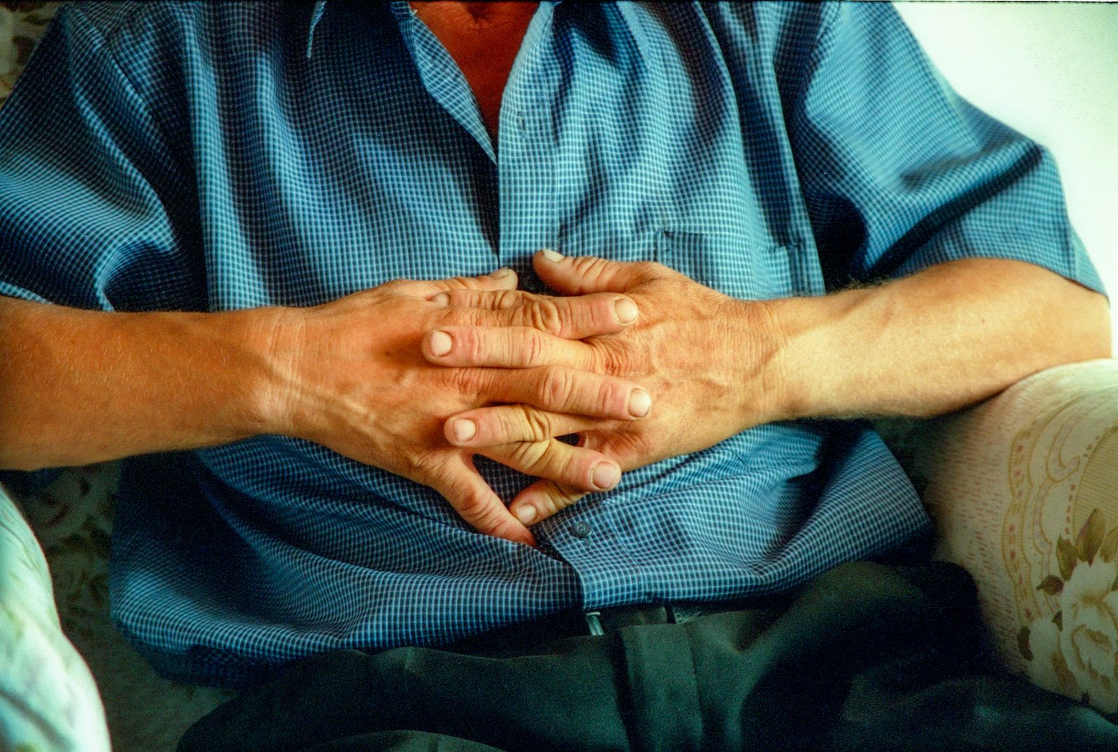 A younger hand gently holding the hands of an older adult
